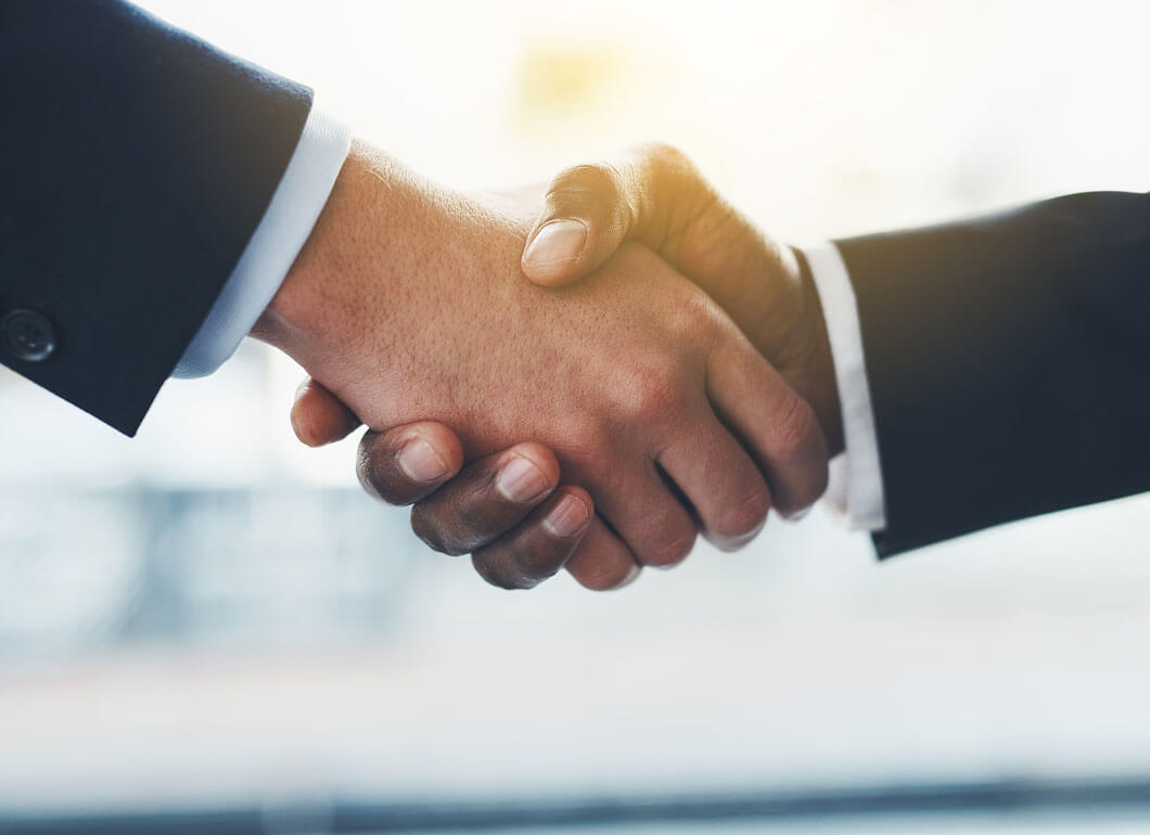 Two business men in suits shaking hands after a deal.