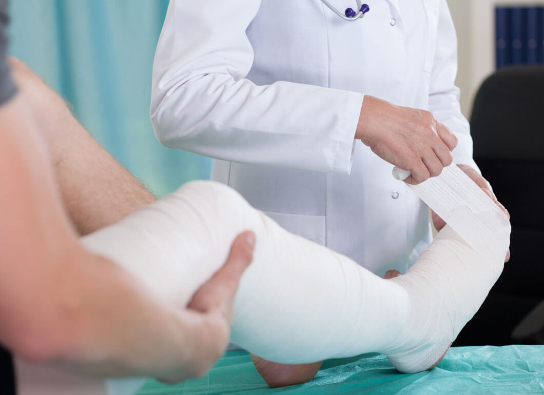A doctor wrapping up a broken leg while preparing for a cast
