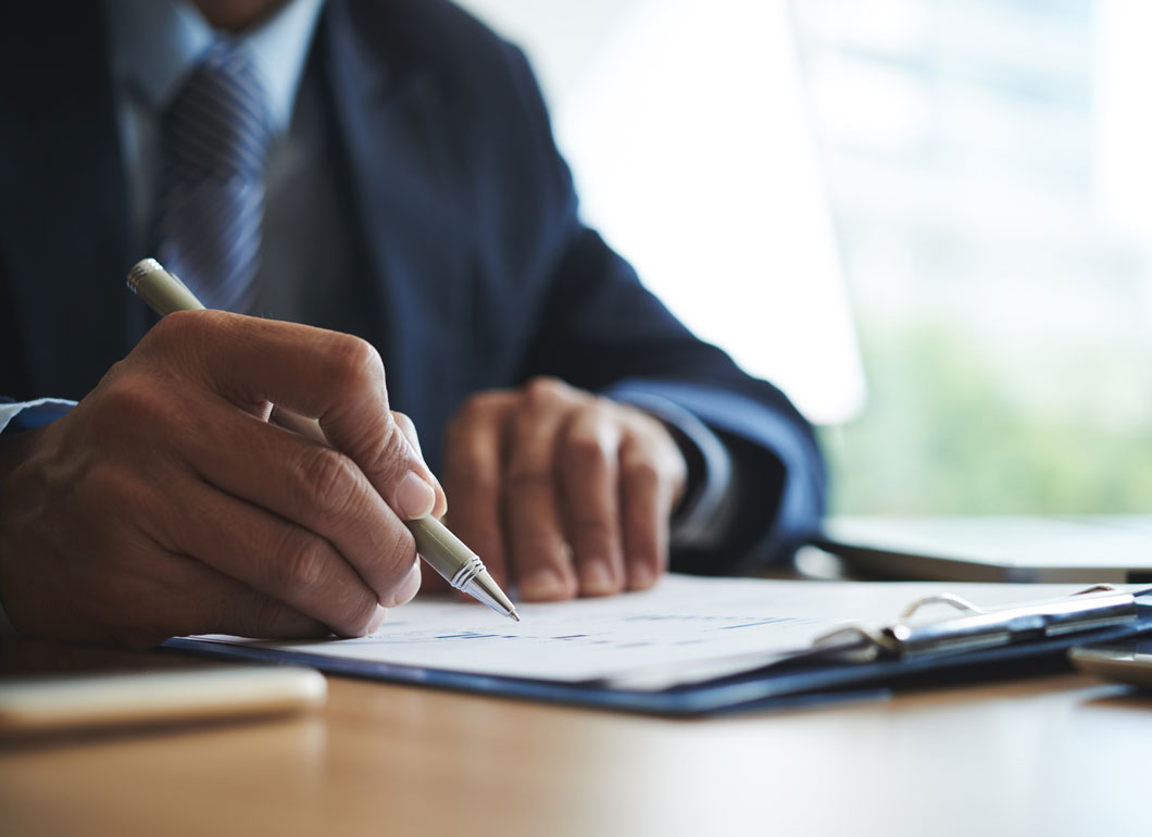 A business person holding a pen while going over some paperwork.