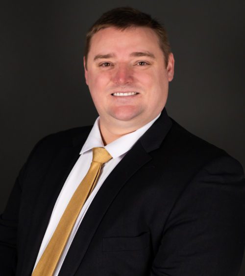 Garret White, attorney at Adams, Hemingway, Wilson & Rutledge, LLC, wearing a black suit with a gold tie